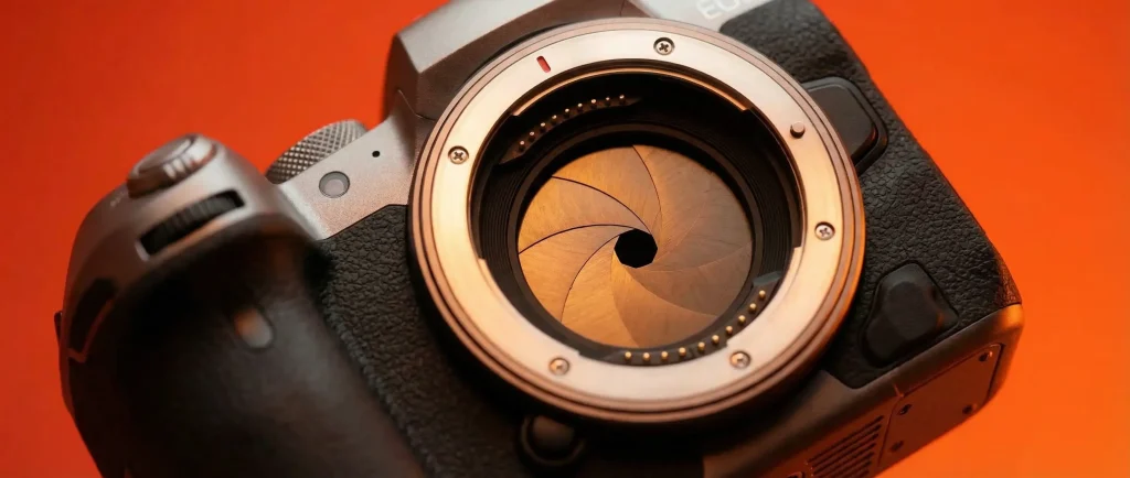 Відкрита діафрагма об’єктива камери крупним планом на теплому фоні