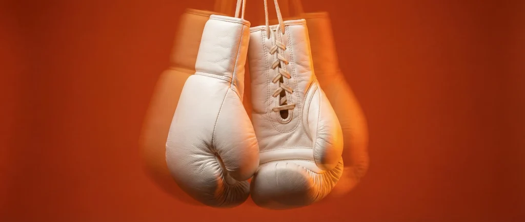 Боксерські рукавиці в русі на помаранчевому фоні як метафора вибору між RAW і JPEG